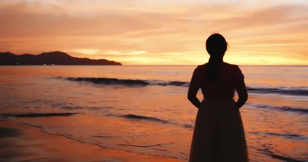 Азиатка стоит на пляже — стоковое видео