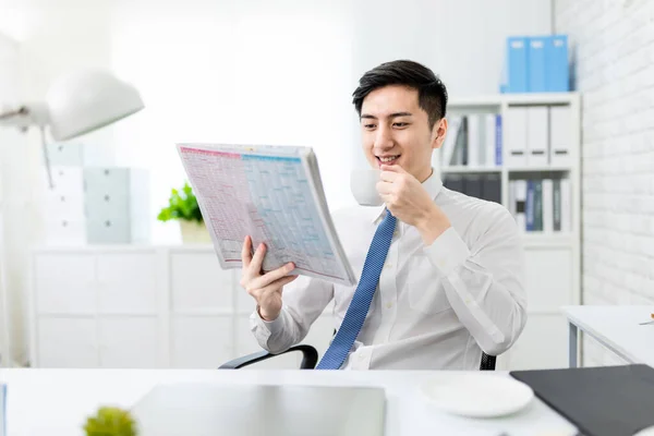 アジアの若いビジネスマンはオフィスで新聞やコーヒーを読んでいます — ストック写真