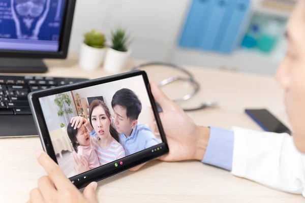 亚洲男性儿科医生的远程医疗概念 在数字平板电脑上听家庭的观点 — 图库照片