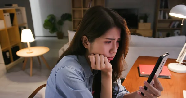 亚洲忧心忡忡的年轻女子看着家里的智能手机 满屏幕上都是软件攻击的话 — 图库照片
