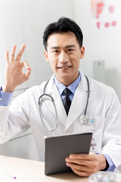 Asyalı Genç Doktorun Dikey Hareketi Klinikte Dijital Tabletle Gülümsemesi — Stok fotoğraf