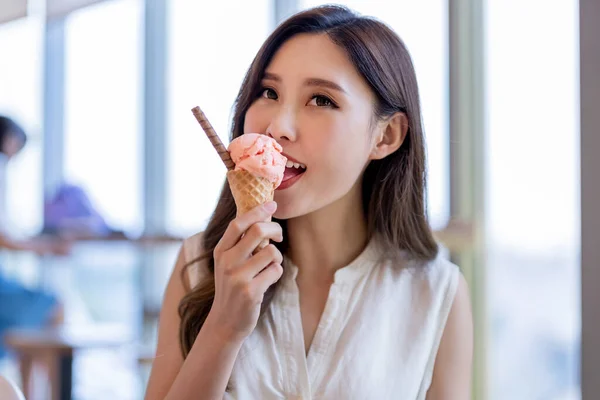 asian young woman eat ice cream dessert in waffle cone at restaurant