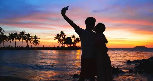 アジア人夫婦のシルエットは日没時にセルフィーをとってビーチで抱き合って — ストック写真