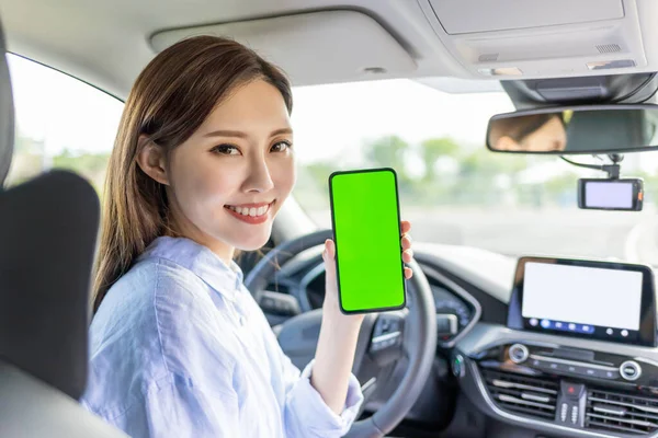 Asian female driver  sit in the car and show her smartphone with green screen