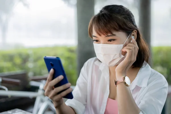 Asiatisk Ung Kvinne Bærer Beskyttende Maske Øretelefon Bruk Smarttelefon Utendørs – stockfoto