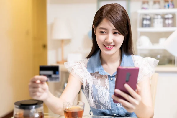 亚洲女人在网上购物 在家里用智能手机用信用卡付账 — 图库照片