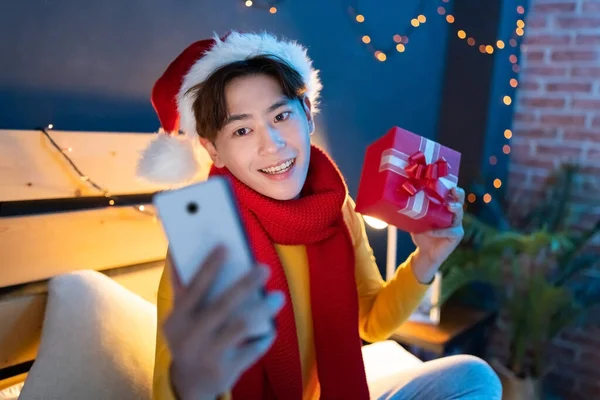 Eşarp Noel Şapkası Takan Asyalı Genç Adam Akıllı Telefonda Görüntülü — Stok fotoğraf