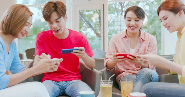 아시아의 친구들은 카페에서 스마트폰으로 재미있는 게임을 공유하고 있습니다 — 스톡 사진