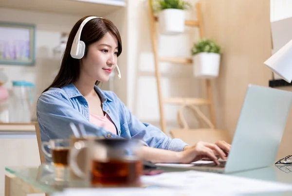 亚洲女商人使用带耳机的笔记本电脑 在家工作 — 图库照片