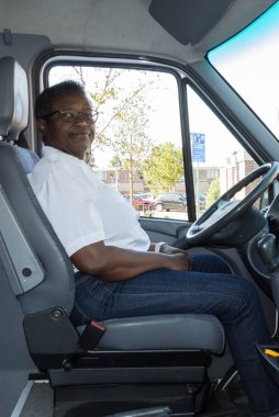 nişasta Beyaz gömlekli bir kadın afro Amerikan Karayip otobüs şoförü onu araç yolcular için bekleyen oturuyor