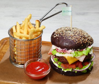 Burger bir ahşap tahta üzerinde sığır eti, patates kızartması, sos ile.