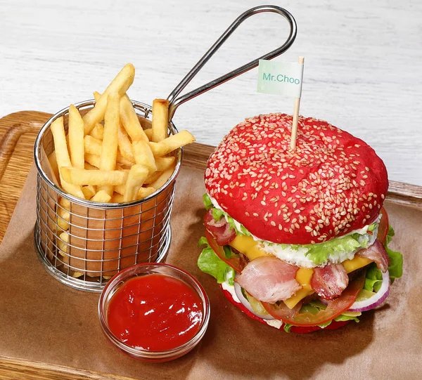 Burger bir ahşap tahta üzerinde domuz eti, patates kızartması, sos ile.