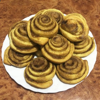 Tarçın kahverengi bir masa arka plan üzerinde bir tabak üzerinde rulo