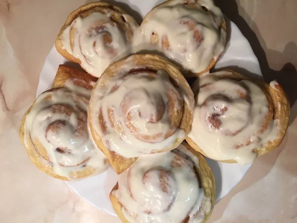 Sinnabon çörekleri. Beyaz bir tabakta krem peynir ile Cinabon rulo