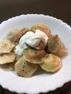 Beyaz tabakta biberli ve ekşi kremalı hamur tatlısı.