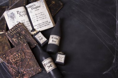 Cadılar Bayramı için bir kara tahta zemin üzerine örümcek ağları ve iksir şişesi ile eski büyü kitapları. 