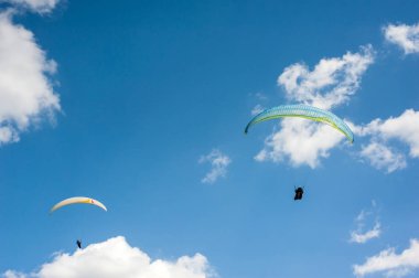 İki paraşütler bulutlar arka planı mavi gökyüzünde uçan. Güneşli bir havada yamaç paraşütü.