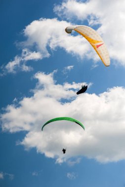 İki paraşütler bulutlar arka planı mavi gökyüzünde uçan. Güneşli bir havada yamaç paraşütü.