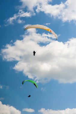 İki paraşütler bulutlar arka planı mavi gökyüzünde uçan. Güneşli bir havada yamaç paraşütü.