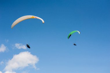 İki paraşütler bulutlar arka planı mavi gökyüzünde uçan. Güneşli bir havada yamaç paraşütü.