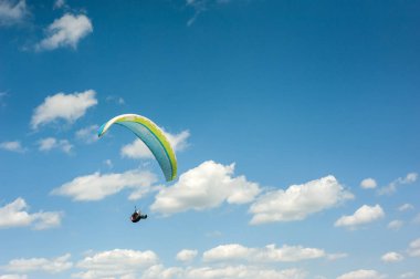 Yamaçparaşütü bulutlar arka planı mavi gökyüzünde uçan. Güneşli bir havada yamaç paraşütü.