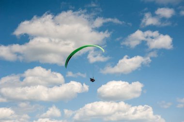 Yamaçparaşütü bulutlar arka planı mavi gökyüzünde uçan. Güneşli bir havada yamaç paraşütü.