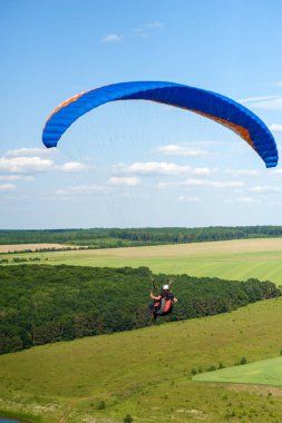 Yamaç paraşütü yaz güneşli günde yeşil alanın üzerinde. Bir yamaçparaşütü uçmak Ukrayna Dnister Nehri yakınında yeşil alanın üzerinde.