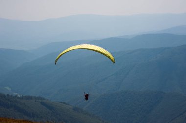 Yamaçparaşütü bir güneşli yaz gününde bir dağ Vadisi uçar. Karpatlar yaz aylarında yapılan yamaç paraşütü.