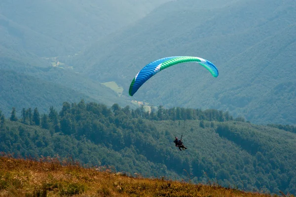 Yamaçparaşütü bir güneşli yaz gününde bir dağ Vadisi uçar. Karpatlar yaz aylarında yapılan yamaç paraşütü.