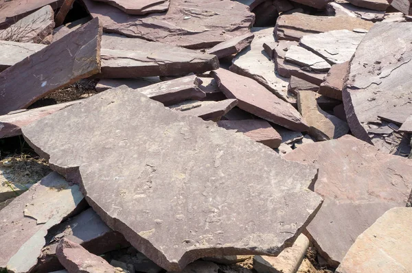 Stone sandstone (slate) is chopped on construction work. A stone of sandstone lies on a pile for building a house.