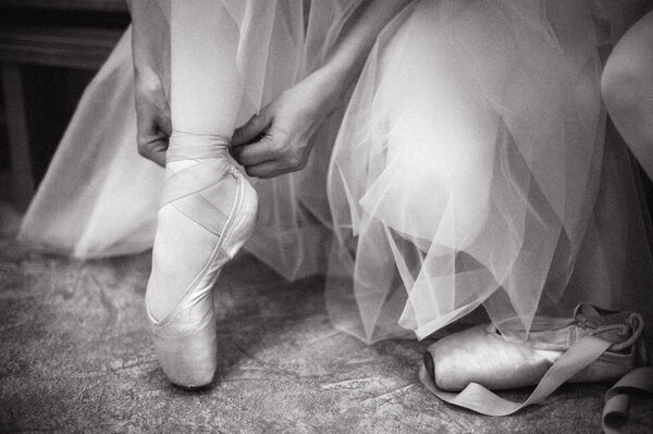 Young ballerina wearing pointe shoes. Close-up of a ballerina's pointe shoes in the dance hall. Vintage photography.