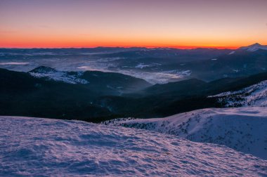 Kışın şaşırtıcı gündoğumu dağlarda. Kış soğuk sabah güneşin ışınları dağlarda zirveleri karla kaplı.