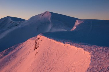 Kışın şaşırtıcı gündoğumu dağlarda. Kış soğuk sabah güneşin ışınları dağlarda zirveleri karla kaplı.
