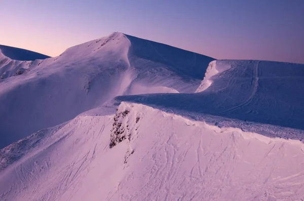 Amazing sunrise in the mountains in winter. Snow-covered peaks of mountains in the rays of the sunrise in the winter frosty morning.