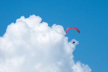 Bulutlar arka planı mavi gökyüzünde uçan bir yamaçparaşütü. Güneşli bir havada yamaç paraşütü.