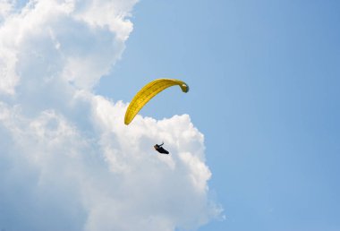 Yamaçparaşütü bulutlar arka planı mavi gökyüzünde uçuyor. Güneşli bir havada yamaç paraşütü.