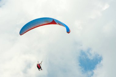 Yalnız yamaçparaşütü bulutlar arka planı mavi gökyüzünde uçan. Güneşli bir havada yamaç paraşütü.