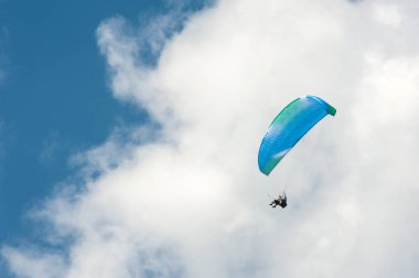 Yalnız yamaçparaşütü bulutlar arka planı mavi gökyüzünde uçan. Güneşli bir havada yamaç paraşütü.