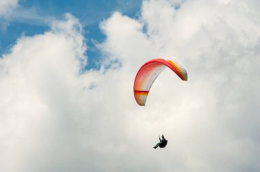 Yalnız yamaçparaşütü bulutlar arka planı mavi gökyüzünde uçan. Güneşli bir havada yamaç paraşütü.