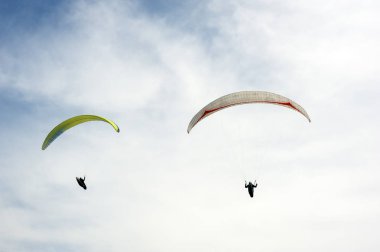 İki paraşütler bulutlar arka planı mavi gökyüzünde uçan. Güneşli bir havada yamaç paraşütü.