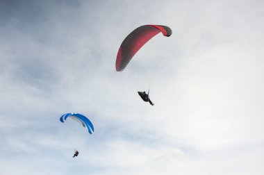 İki paraşütler bulutlar arka planı mavi gökyüzünde uçan. Güneşli bir havada yamaç paraşütü.