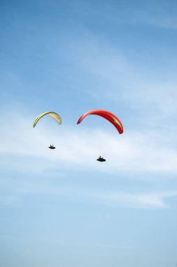 İki paraşütler bulutlar arka planı mavi gökyüzünde uçan. Güneşli bir havada yamaç paraşütü.