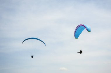 İki paraşütler bulutlar arka planı mavi gökyüzünde uçan. Güneşli bir havada yamaç paraşütü.