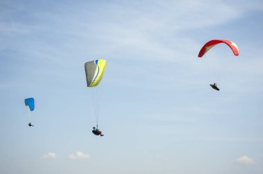 İki paraşütler bulutlar arka planı mavi gökyüzünde uçan. Güneşli bir havada yamaç paraşütü.