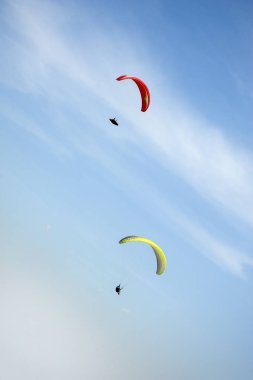 İki paraşütler bulutlar arka planı mavi gökyüzünde uçan. Güneşli bir havada yamaç paraşütü.