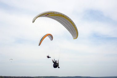 İki paraşütler bulutlar arka planı mavi gökyüzünde uçan. Güneşli bir havada yamaç paraşütü.