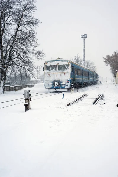 Train on the railway in heavy snow storm. Passenger train moves on the railway in winter in Ukraine.