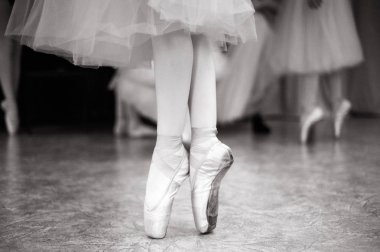 Balerin dans salonunda eğitiyor. Balerin'ın bacakları dans salonunda Close-up. Siyah beyaz fotoğraf.