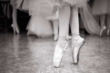 Balerin dans salonunda eğitiyor. Balerin'ın bacakları dans salonunda Close-up. Siyah beyaz fotoğraf.