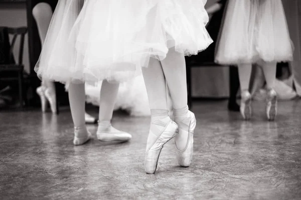 バレリーナは ダンスホール トレーニングです ダンスホールでバレリーナの足のクローズ アップ 黒と白の写真 — ストック写真